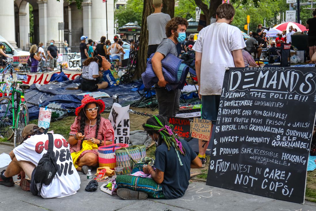 Protesters occupy the area outside of City Hall, with blankets, hammocks, signs, snacks, water
